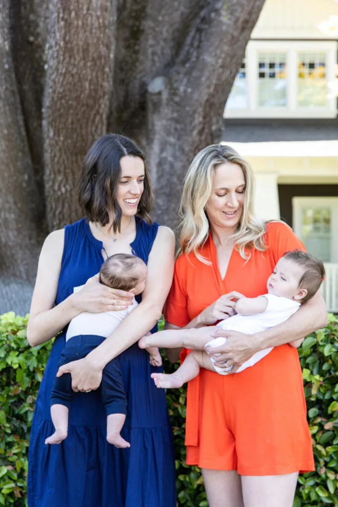 two moms holding babies outside